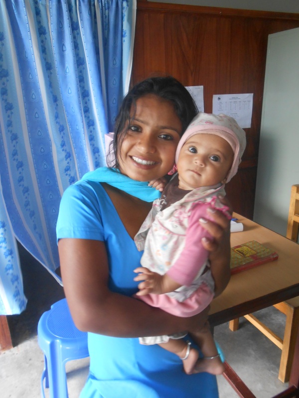 Gita holding a baby coming in for a check up